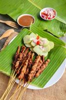 chicken satay or chicken satay served with lontong, rice cake and peanut sauce. served on banana leave photo