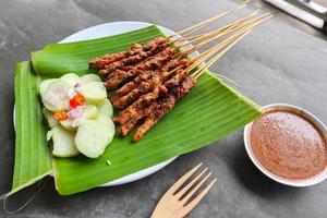 pollo satay o pollo satay servido con mucho tiempo, arroz pastel y maní salsa. servido en plátano salir foto