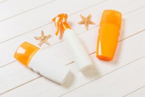 flat lay concept summer travel vacation. Sunscreen bottles with starfish on white wooden table with copy space photo