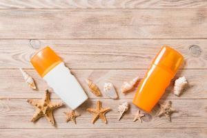 botellas de protección solar con conchas marinas y estrellas de mar sobre una mesa de madera con espacio para copiar. concepto plano de viaje de vacaciones de verano foto