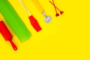 culinary accessories on a yellow background, rolling pin, brush, silicone mat, dough knife, skewers, culinary background with copy space photo