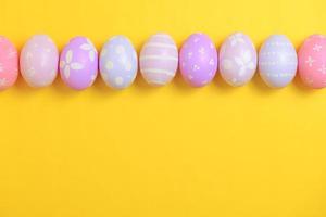 Happy easter holiday celebration concept. Group of painted colourful eggs decoration on a yellow background. Seasonal religion tradition design. Top view, flat lay, copy space. photo