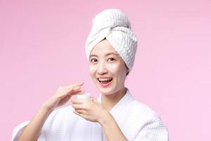 Young asian woman applying facial skincare face cream, cosmetic moisturiser on healthy natural skin make up face. Portrait glowing smile girl person model with care beauty product, spa, cosmetology. photo