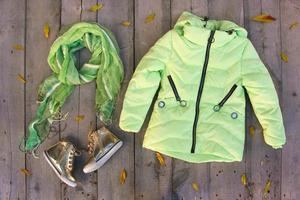 Children's autumn clothes and yellow leaves on old wooden background. Top view. Flat lay. photo