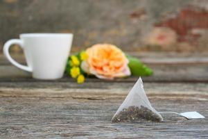 Tea bag on background of rose and and cup of tea. photo