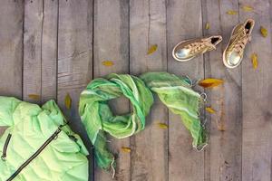 Children's autumn clothes and yellow leaves on old wooden background. Top view. Flat lay. photo