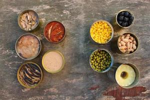 Different open canned food on old wooden background. Top view. Flat lay. photo