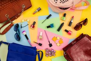 Things from open lady purses. Cosmetics and women's accessories fell out of different handbags on colourful background. Top view. photo