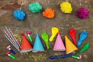 Holiday hats, whistles, balloons on old wooden background. Concept of children's birthday party. Top view. photo