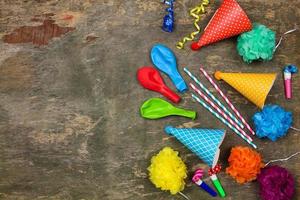 Holiday hats, whistles, balloons on old wooden background. Concept of children's birthday party. Top view.