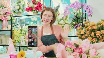 E-Commerce Geschäft, einer jung Weiß weiblich Florist demonstriert und zeigt an Blumen- Vereinbarungen über online Leben Streaming mit Smartphone Anwendung im hell Blume Geschäft, schön Blüten speichern. video