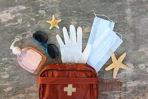 First aid kit on old wooden background. Concept of protect yourself from COVID-2019 in journey. Top view. photo