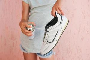 Female hand holding a spray deodorant for shoes. photo