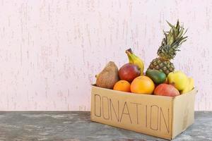 Donation box with food on old wooden background. photo