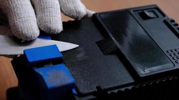 Sharpening a knife on an electric sharpener at home. The man's hand drives the knife blade between the blue sharpeners, dust flies on the machine. 4k, slow motion video