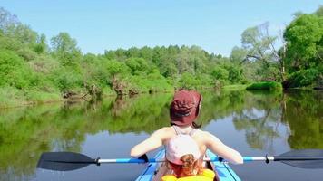 família caiaque viagem. mãe e filha remo uma barco em a rio, uma água caminhada, uma verão aventura. ecológico e extremo turismo, ativo e saudável estilo de vida video
