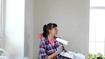 intrigado mulher dentro pintura rolo e branco pintura para paredes dentro mãos fechar-se retrato. construção trabalhos e Cosmético reparos dentro casa, parede pintura, tingimento, acabamento trabalhos com seu próprio mãos video