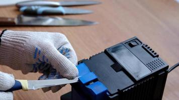 verscherping een mes Aan een elektrisch slijper Bij huis. de man's hand- schijven de mes blad tussen de blauw slijpers, stof vliegt Aan de machine. 4k, langzaam beweging video