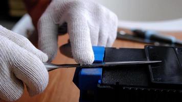 Sharpening a knife on an electric sharpener at home. The man's hand drives the knife blade between the blue sharpeners, dust flies on the machine. 4k, slow motion video