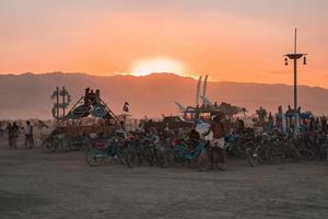 personas caminando hacia puesta de sol a un festival en el Desierto a el ardiente hombre festival. foto