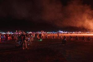 personas caminando hacia puesta de sol a un festival en el Desierto a el ardiente hombre festival. foto