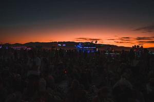 personas caminando hacia puesta de sol a un festival en el Desierto a el ardiente hombre festival. foto