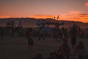 People walking towards sunset at a festival in the desert at the Burning Man Festival. photo