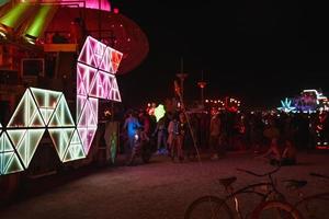 personas caminando hacia puesta de sol a un festival en el Desierto a el ardiente hombre festival. foto