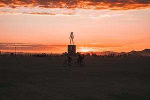 personas caminando hacia puesta de sol a un festival en el Desierto a el ardiente hombre festival. foto