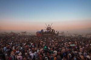 personas caminando hacia puesta de sol a un festival en el Desierto a el ardiente hombre festival. foto