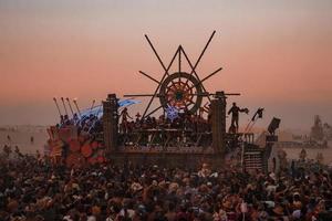 personas caminando hacia puesta de sol a un festival en el Desierto a el ardiente hombre festival. foto