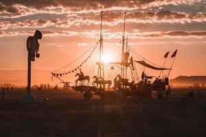 personas caminando hacia puesta de sol a un festival en el Desierto a el ardiente hombre festival. foto