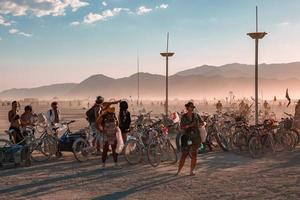 personas caminando hacia puesta de sol a un festival en el Desierto a el ardiente hombre festival. foto