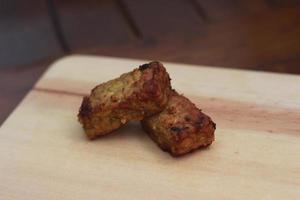 a close up of fried tempeh on a wooden cutting board photo