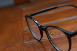 a close up of eyeglasses with black frames isolated natural patterned wooden background. photo