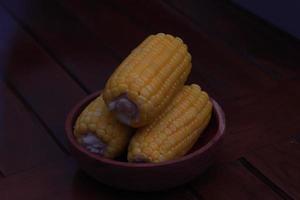 a close up of corn on the cob served in a wooden bowl. photo