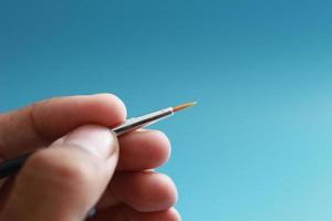 a close up of a hand holding a painting brush photo