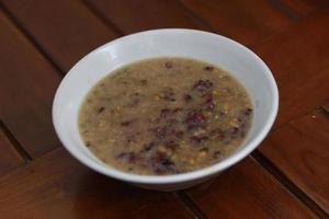 a close up of a bowl of green bean porridge and black sticky rice doused in coconut milk photo