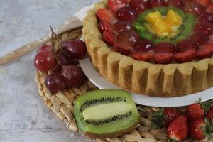 grande Fruta tarta con coberturas de fresas, uvas, kiwi y piña. sabroso, dulce y fresco. comida concepto foto. foto