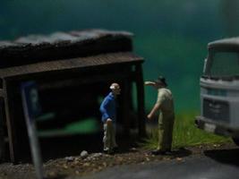 un cerca arriba de un miniatura figura de un antiguo hombre hablando a otro personas en un antiguo edificio por el lado de el la carretera. foto