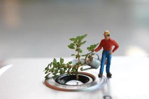 un miniatura figura de un granjero riego un en conserva planta en el formar de un término análogo cámara lente. foto