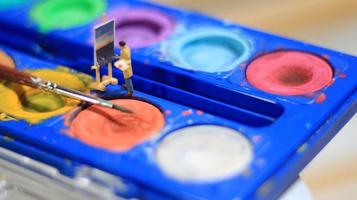 a miniature figure of a painter painting a landscape on watercolors. artist concept. photo