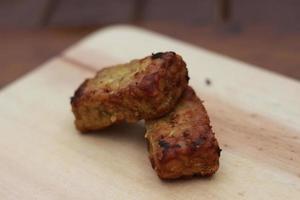 a close up of fried tempeh on a wooden cutting board photo