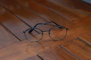 a close up of eyeglasses with black frames isolated natural patterned wooden background. photo