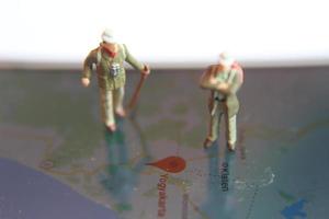 miniature figure of an explorer posing on a digital map via a mobile phone photo