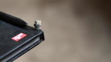 a view of miniature figure reading a newspaper on a book. photo