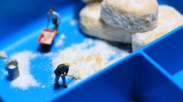 a miniature figure of a worker tidying a peanut cake sprinkled with powdered white sugar. concept of workers in the food industry. photo