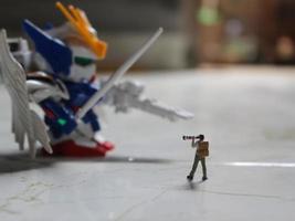 miniatura figura de un fotógrafo tomando un foto de un robot.