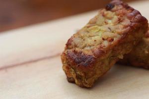 a close up of fried tempeh on a wooden cutting board. photo