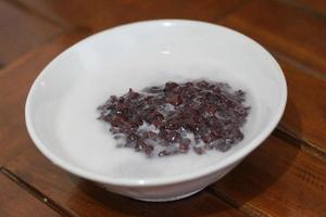 a bowl of black sticky rice porridge with coconut milk photo